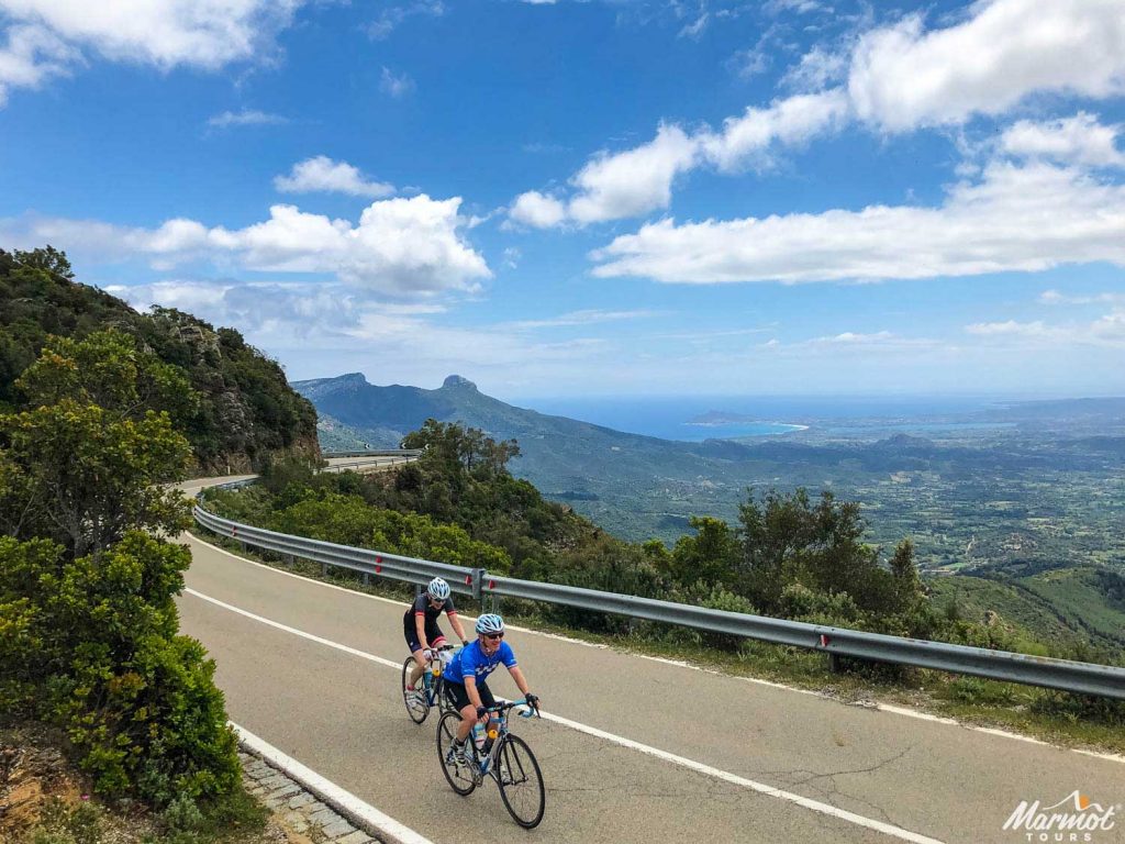 Cyclists climbing on Sardinia with sea in background on Marmot Tours fully supported road cycling holidays in Europe