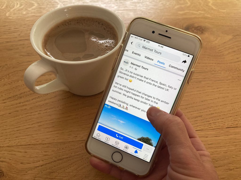 Person holding mobile phone showing Marmot Tours Facebook post