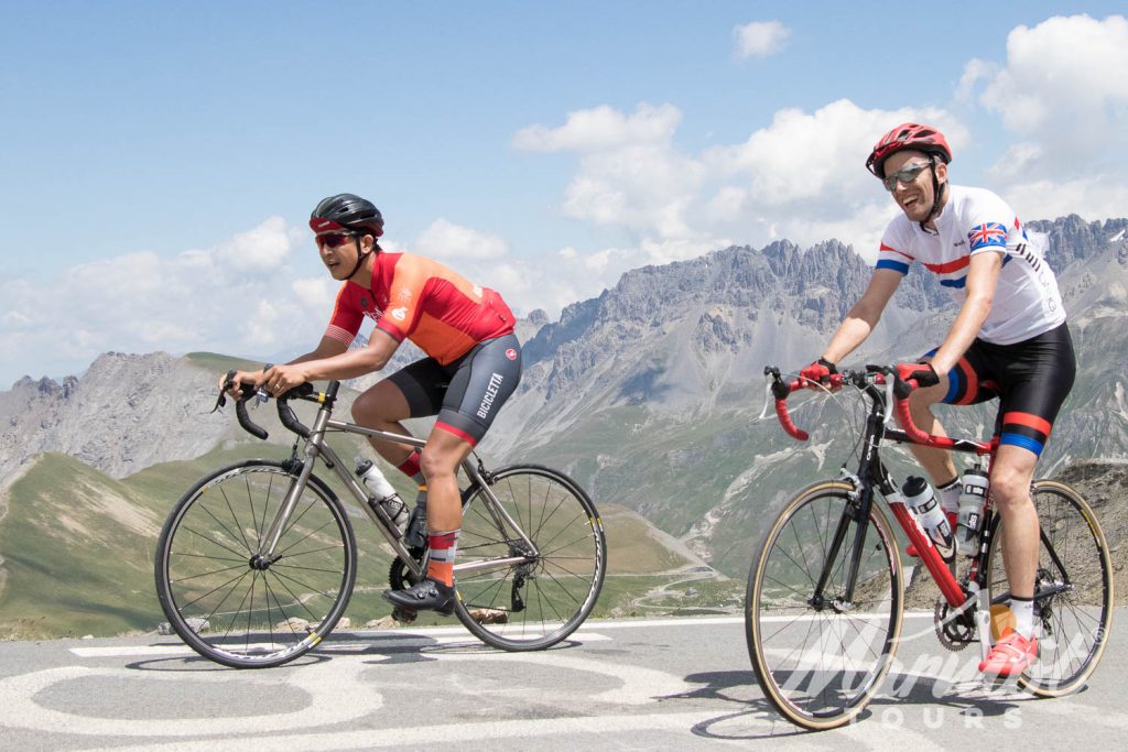 Two cyclists laughing on summit with Marmot Tours road cycling holidays in the Alps