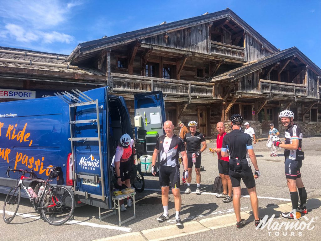Group of cyclists enjoying snacks from Marmot Tours support vehicle on fully supported road cycling holiday in French Alps