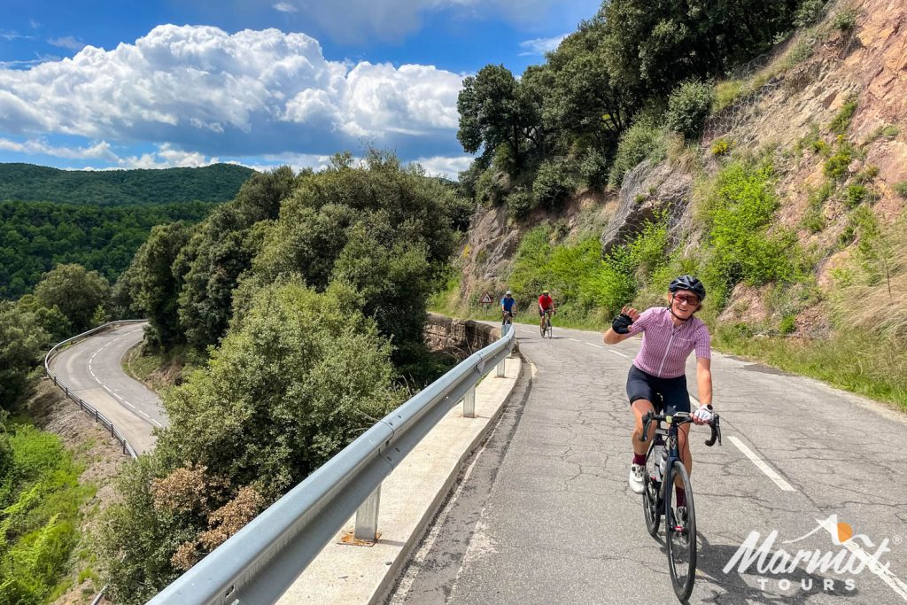 Cyclists waving while climbing on Marmot Tours fully supported road cycling holiday in Spain Catalonia Girona