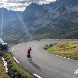 Cyclist and Marmot Tours support van on Col du Tourmalet hairpin bend in French Pyrenees
