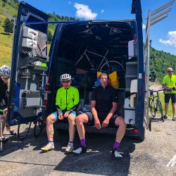 Cyclists enjoying rest and snacks at support vehicle on Marmot Tours guided road cycling holiday of French Pyrenees