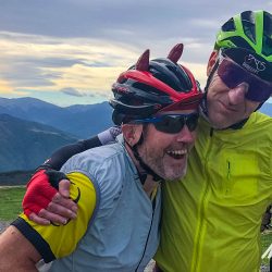 Two cyclists hugging and laughing on Raid Pyrenean cycling challenge with Marmot Tours