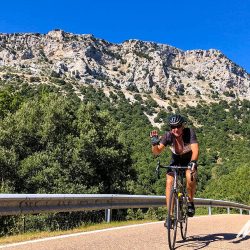 Cyclist waving on sunny ride enjoying guided cycling tour of Sardinia with Marmot Tours