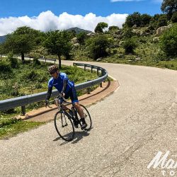 Cyclist descending in sun on full support road cycling tour of Sardinia with Marmot Tours