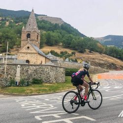 Female cyclist climbing Alpe d'Huez with church in background on Marmot Tours guided cycling tour of French Alps