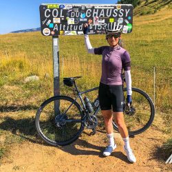 Female cyclist happy at Col du Chaussy sign on Marmot Tours guided cycling tour of French Alps