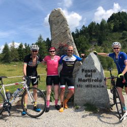 Group of cyclists smiling at Passo Mortirolo summit on Marmot Tours full support road cycling holiday Dolomites Italy