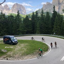 Cyclists climbing hairpin ben with Marmot Tours support vehicle on standby on guided road cycling tour of Dolomites Italy