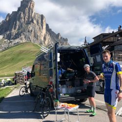 Cyclists at pass Giau enjoying snacks from Marmot Tours support van on road cycling tour of Dolomites Italy