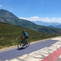 Cyclist summiting Col de la Madeleine on Marmot Tours supported road cycling tour French Alps
