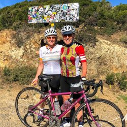 Pair of female cyclists smiling at col sign on Marmot Tours guided road cycling tour of Corsica