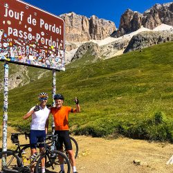 Pair of cyclists thumbs up at Passo Pordoi on Marmot Tours guided road cycling holiday Dolomites Italy