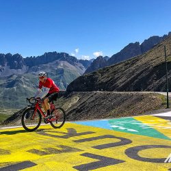 Cyclist summiting Galibier on Marmot Tours Raid Alpine cycling challenge