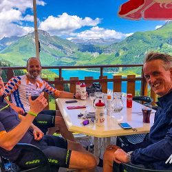 Group of cyclists enjoying cafe break above Lac Roselend on Marmot Tours Raid Alpine cycling challenge French Alps