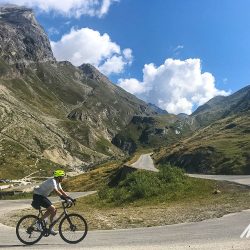 Cyclist climbing Col de l'Iseranon Marmot Tours Raid Alpine cycling challenge French Alps