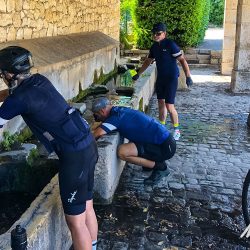 Cyclists filling water bottles in French squareon Marmot Tours Raid Alpine cycling challenge French Alps