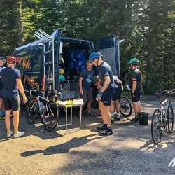 Group of cyclists enjoying rest break for snacks at support vehicle on Marmot Tours Raid Massif Central French cycling holidays