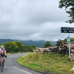 Cyclist summiting Col de Pertus on Marmot Tours Raid Massif Central French cycling holidays