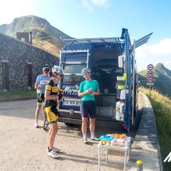 Cyclists enjoying snacks from support vehicle at summit of Pas de petrol Puy Mary on Marmot Tours Raid Massif Central French cycling holidays