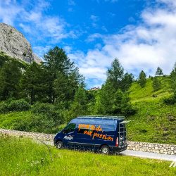 Cyclist climbing near Marmot Tours support vehicle on guided road cycling tour Dolomites Italy