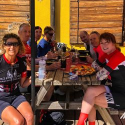 Group of happy cyclists enjoying pizza on full support road cycling holiday with Marmot Tours