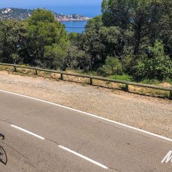 Cyclist in sunshine on coast road Tossa de Mar on Marmot Tours guided cycling tour Girona Catalonia Spain with full support