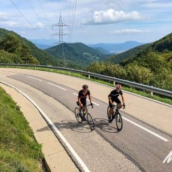 Pair of cyclists climbing in sunshine on Marmot Tours guided cycling tour Girona Catalonia Spain with full support