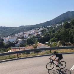 Cyclist and white village on hillside on Marmot Tours guided group road cycling tour Andalusia Spain