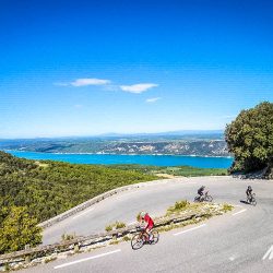 Cyclists rounding hairpin bend on climb above Verdon Gorge on Marmot Tours guided road cycling tour Mont Ventoux Provence France