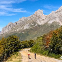 Pair of cyclists climbing with mountains backdrop in Picos de Europa Northern Spain guided road cycling tour with Marmot Tours
