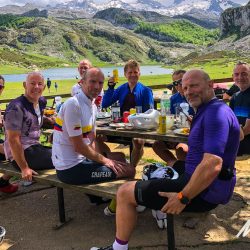 Group of cyclists enjoy cafe stop lakeshore in Picos de Europa Northern Spain with Marmot Tours road cycling holidays