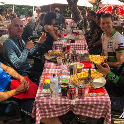 Group of cyclists enjoy pizza for lunch in Southern Alps on Marmot Tours fully supported road cycling holiday