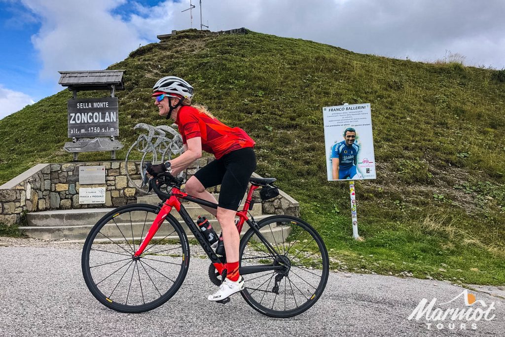 Female cyclist summiting Monte Zoncolan cycling climb with Marmot Tours guided road cycling holidays Slovenia