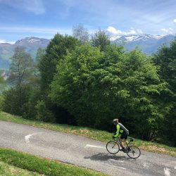 Cyclist on steep climb with Pyrenees backdrop with Marmot Tours