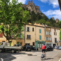 cyclist in Foix beneath chateau on Marmot Tours guided group cycling holiday Foothills Pyrenees