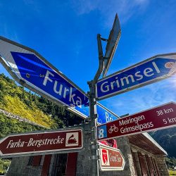 Road signs for Furka and Grimsel Pass cycling climbs on Marmot Tours guided road cycling tour Swiss Alps
