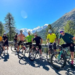 Group of cyclists smiling in Swiss Alps with backdrop of glacier on Marmot Tours Raid Dolomites challenge