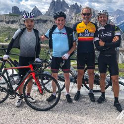 Group of cyclists smiling with mountain peak backdrop on Raid Dolomites with Marmot Tours