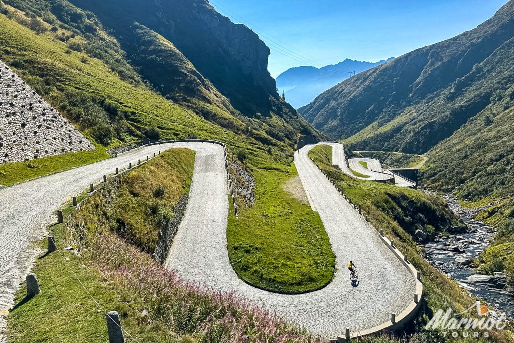 Cyclist descending cobbles of San Gotthard pass in Swiss Alps on Marmot Tours guided road cycling holiday