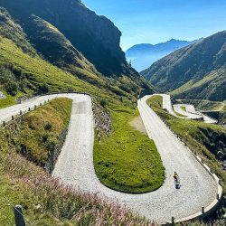 Cyclist descending cobbles of San Gotthard pass in Swiss Alps on Marmot Tours guided road cycling holiday