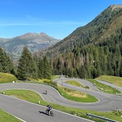 Cyclist descending hairpins of Passo Pordoi cycling climb on Raid Dolomites guided support cycling challenge with Marmot Tours