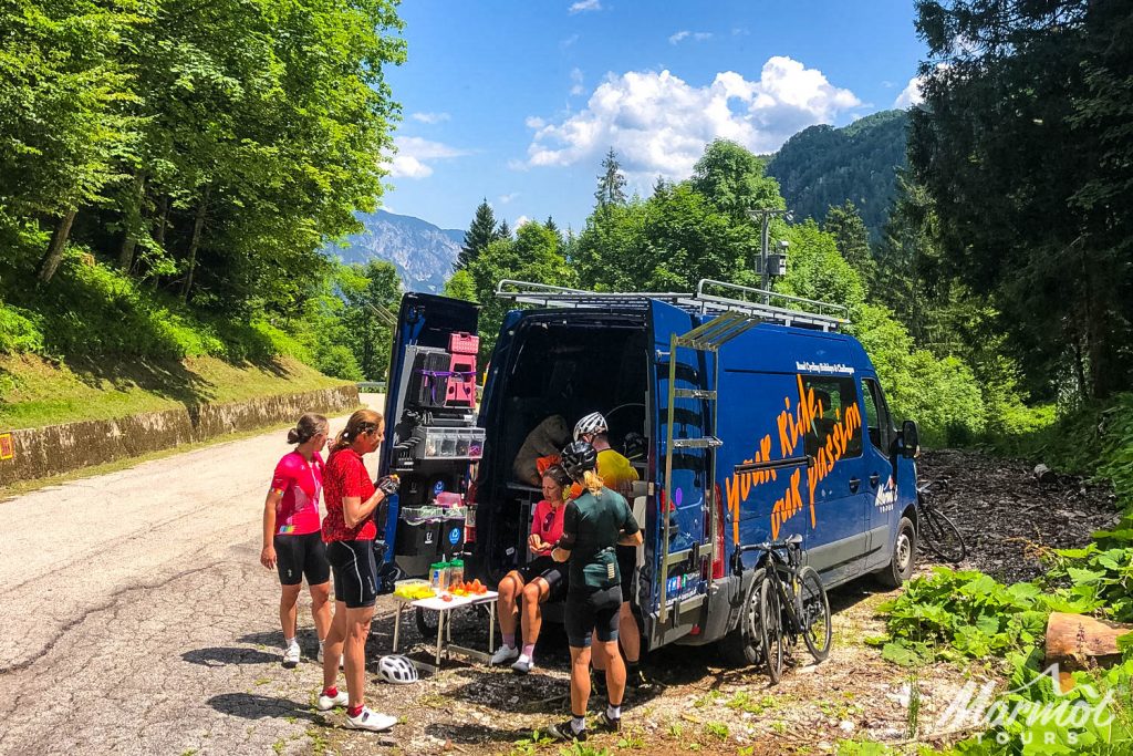 Cyclist enjoying snacks and drinks from support vehicle on Marmot Tours guided road cycling tour of Swiss Alps