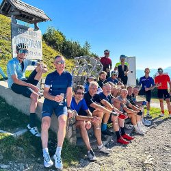 Group of cyclists celebrating with champagne at summit of Monte Zoncolan road cycling holiday Raid Dolomites with Marmot Tours