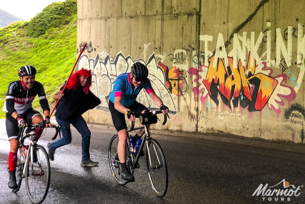 Pair of cyclists being chased by cycling died in devil costume on Marmot Tours guided cycling holiday French Pyrenees