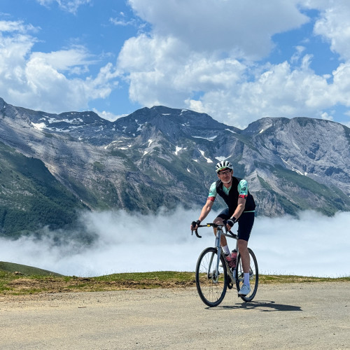cyclist summiting col daubisque with mountain backdrop and cloud inversion on marmot tours Atlantic to mediterranean cycling holiday