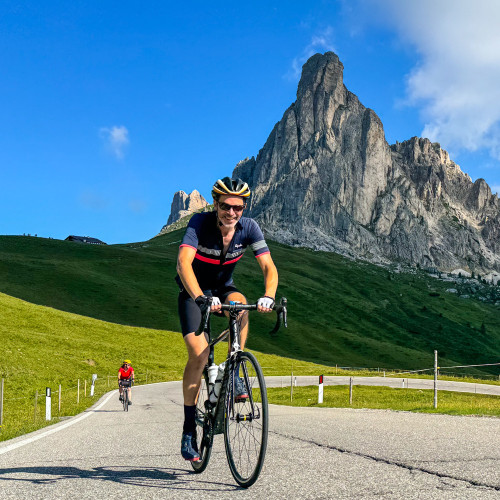 cyclists climbing passo giau with dolomites peak backdrop on marmot tours guided cycling tour of dolomites