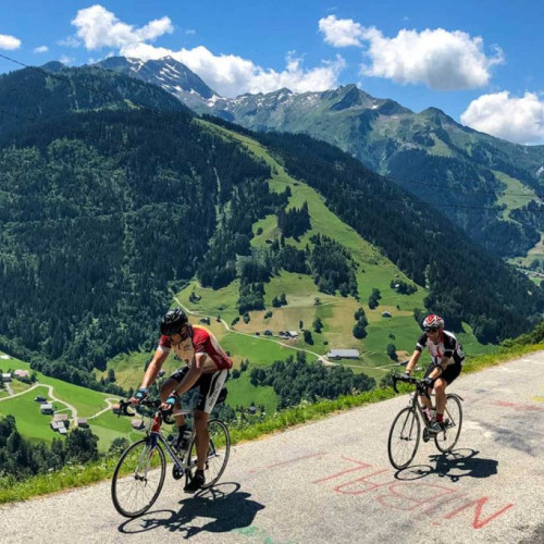 Pair of cyclists climbing in French Alps on Marmot Tours guided road cycling tour mountains backdrop
