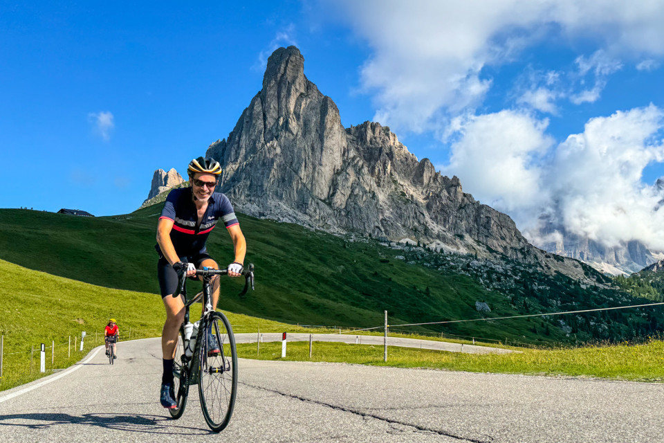 cyclists climbing passo giau with dolomites peak backdrop on marmot tours guided cycling tour of dolomites